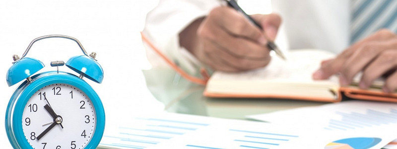 Der beste Zeitpunkt für den Immopbilienverkauf - Mann kalkuliert, während Wecker tickt