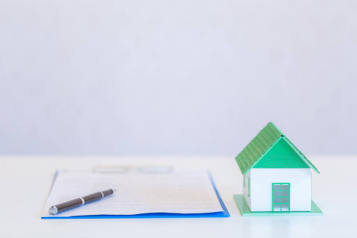 Immobilienkauf: Symbolfoto mit Unterlagen und Hausmodell