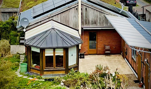 Sustainable bungalow with a conservatory, garage, and garden.