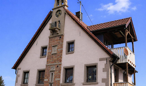 Half-detached house with exposed timber frame construction, featuring a garden, balconies, and a covered outdoor seating area, located in Tübingen-Bühl.
