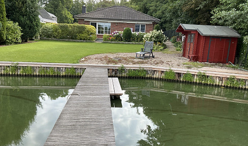 Wassergrundstück mit Bungalow und Bootssteg.