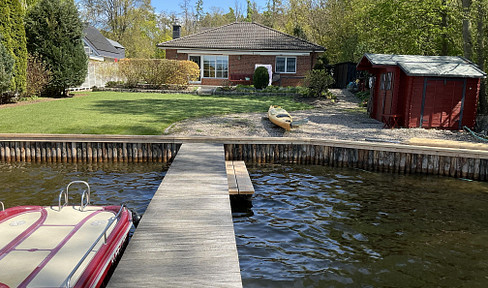 Wassergrundstück mit Bungalow und Bootssteg.