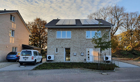 NMS Einfeld: Modern semi-detached house with solar panels and a heat pump.