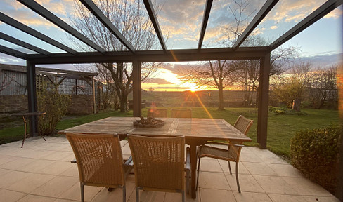 Located on the edge of a field with sunset views, this detached single-family house offers 224 square meters of living space and includes a solar panel system.