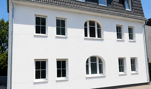 Energy-efficiently renovated multi-family building with modern features, a large garage, and solar panels.