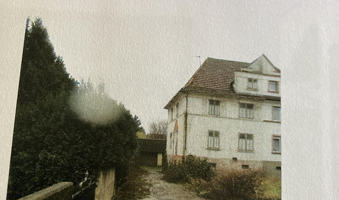 Semi-detached house in need of renovation, featuring a large garden and a garage.