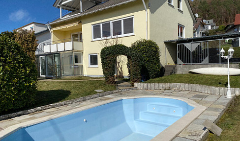 Detached house with lake view, garden, and swimming pool.