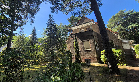 Large property in a green area, featuring a house, garage, carport, and parking spaces.