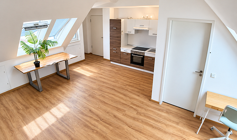 Modern attic apartment with high ceilings, balcony windows, and partial furnishings, located in Frankfurt, in the Europaviertel district.